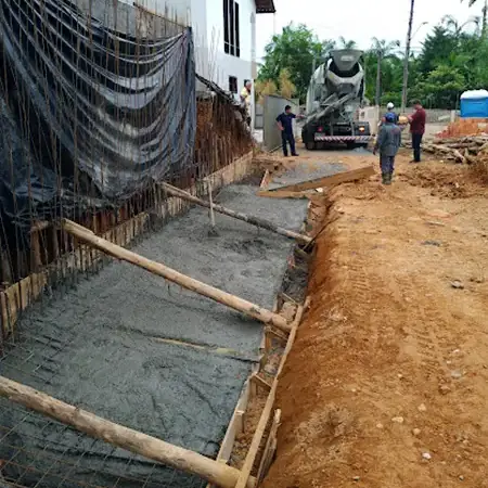 Sapata de muro de contenção com malha de aço e arranques, caminhão betoneira ao fundo