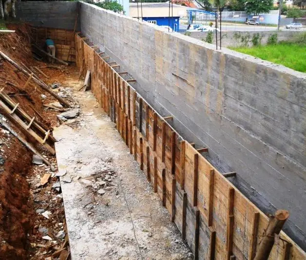 Muro de contenção em concreto armado recém-desformado, com a vala de drenagem ao lado, em Joinville (SC)